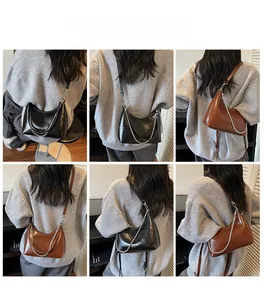 Minimalist crescent bag in black and brown finishes with silver chain details on shoulder