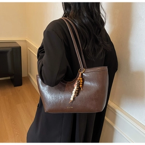 Vue détaillée du sac cabas marron vintage avec pendentif perlé et logo en cuir