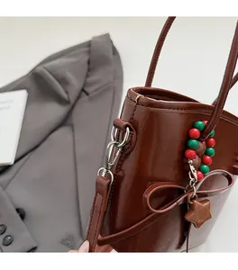 Detail of dark brown leather handbag featuring star charm and silver metal hook