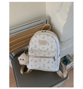 Détail de l'imprimé lapin et du pendentif étoile en peluche sur un sac à dos crème