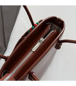 Detailed close-up of smooth silver zipper and glossy brown leather on stylish tote bag