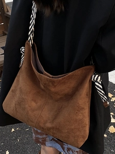 Brown suede tote bag with woven rope strap shown in a casual outdoor street style