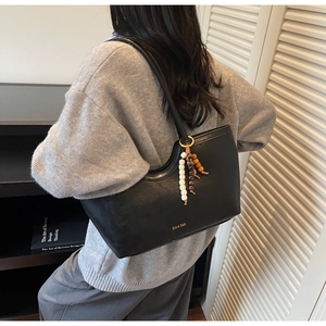 Détail d'un cabas en cuir noir avec logo doré et pendentif de perles colorées élégant