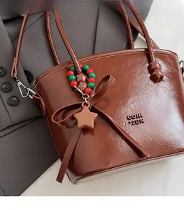 Close-up of dark brown leather handbag featuring a leather bow and colorful bead star charm