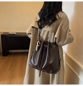 Detail of dark brown leather bucket bag with drawstring and beaded decorative charm