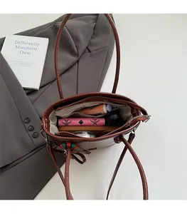 Spacious interior of a brown shoulder bag showing daily items like phone and wallet