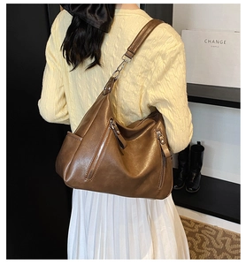 Close-up of brown vintage Hobo shoulder bag with dual vertical zippers and wide strap