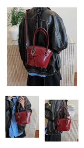 Detail view of burgundy leather handbag with bow decoration and beaded charm