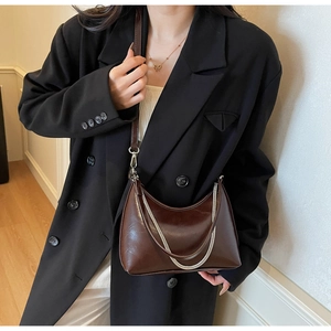 Detailed view of dark brown glossy hobo bag with silver chain and adjustable strap