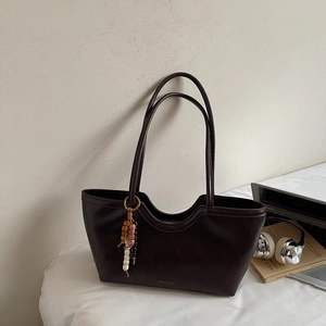 Détail du cabas en cuir marron foncé avec bordure en U et pendentif en perles colorées