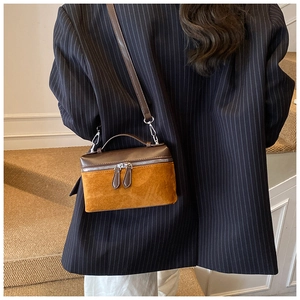 Détail latéral d'un mini sac bandoulière vintage porté avec un blazer bleu marine