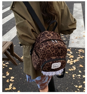 Outdoor shot of leopard print canvas backpack featuring white lace trim and embroidery