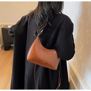 Detail of glossy brown hobo underarm bag with silver zipper and subtle brand logo