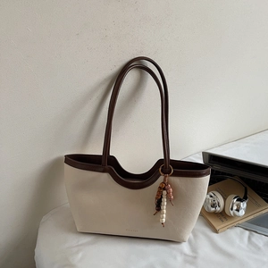 Détail du sac cabas tissé avec bord ondulé et breloque en perles de bois style ethnique