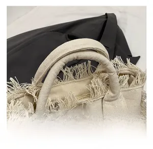 Detail showing the stylish frayed tassel edges and canvas handle of the chic beige tote bag