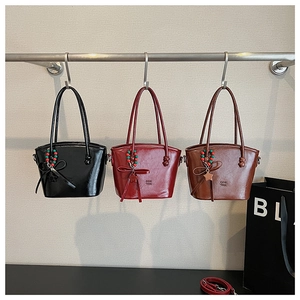 Close-up of stylish faux leather handbags with decorative charms in black, red and brown