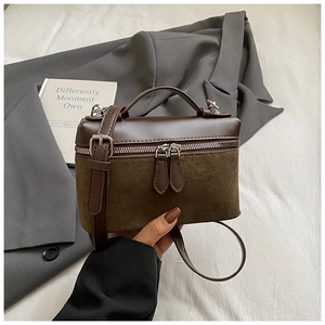Gros plan du sac boîte vintage en cuir marron avec double zip et texture en daim