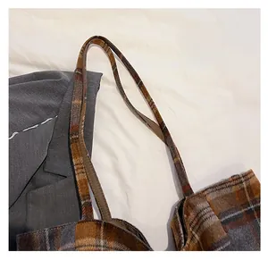 Detail of checkered plaid tote bag strap with brown and grey wool textured fabric