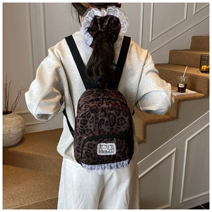 Detail view of mini leopard print backpack with white lace trim and bow patch for women