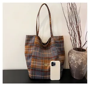 Macro shot of large plaid tote bag showing textured wool fabric and metal brand plate