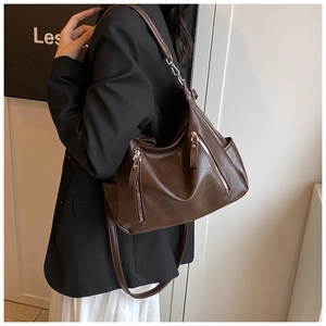 Close-up of brown vintage leather tote bag with stylish side decorative metal zippers