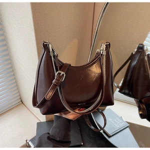 Detail of glossy brown leather shoulder bag with silver zipper and NO FILTER text