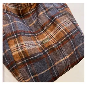 Detail of plaid tote bag featuring textured fabric and a handmade vintage metal label