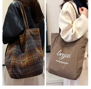 Close-up of a reversible tote bag with vintage plaid pattern and deep brown side details