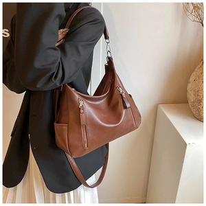 Brown vintage faux leather tote bag with dual zipper pockets and side slots on a model