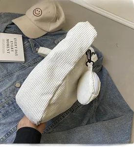 Dettaglio borsa tote in velluto a coste bianco con mini pochette su fondo denim blu
