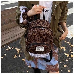 Close-up of leopard print backpack featuring white lace trim and metal zipper detail