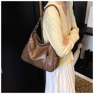 Detailed close-up of brown vintage hobo bag with multiple metal zipper pockets and sleek leather