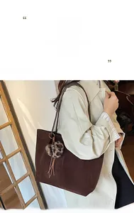 Detail view of large brown suede tote bag with leopard heart charm and tassel accent
