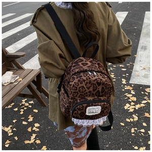 Chic leopard print mini backpack with white lace trim detail in an autumn outdoor setting