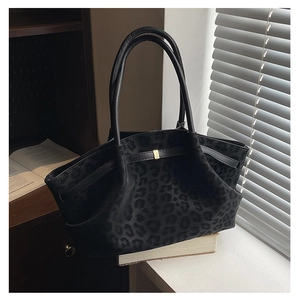 Detail of leopard print suede tote bag with golden metal buckle in artistic scene