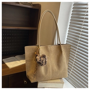 Detail view of khaki tote bag featuring matte texture and leopard heart pendant
