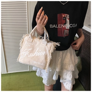 Detail of off-white canvas tote bag featuring fringe edges and summer fashion print