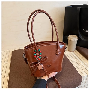Detailed view of dark brown leather handbag featuring a star charm and embossed logo