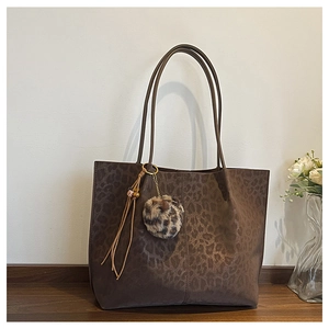 Detail of dark brown leopard print tote bag with faux fur pom-pom and leather tassels