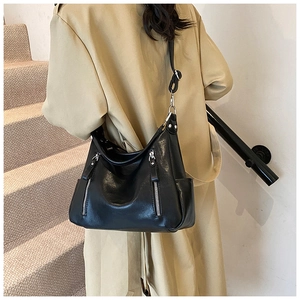 Detail of black vintage shoulder bag with dual silver zippers and side pockets on beige coat