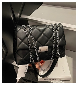 Detail of black quilted crossbody bag with silver twist lock and chain strap