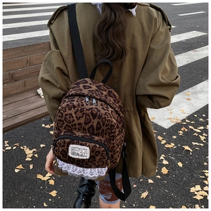 Mini leopard print backpack for women with white lace trim shown in an autumn street scene