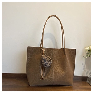 Detail of leopard embossed tote bag with plush pom-pom and leather tassel charms