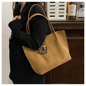 Detailed view of vintage brown suede tote bag with leopard print pom-pom charm on shoulder