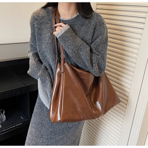 Detail of vintage brown leather tote bag with glossy finish and slim shoulder strap