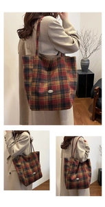 Detail view of retro plaid tote bag with red and black tartan texture and metal logo