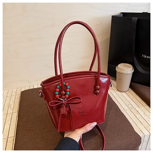 Detail of the glossy red patent leather bucket bag with bow and beaded charm
