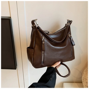 Close-up of deep brown faux leather tote with textured surface and silver zipper details