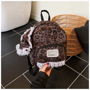 Detail of leopard print mini backpack with white lace trim and large decorative bow