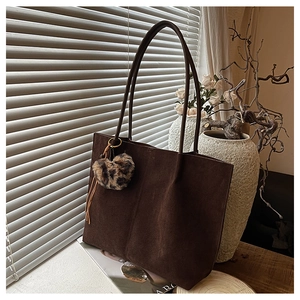 Detailed close-up of brown suede tote bag with leopard print heart and tassel charm